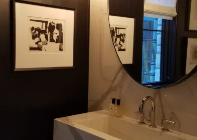 A bathroom with a round mirror and black walls.
