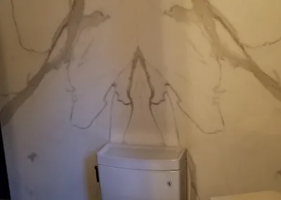 A toilet in a bathroom with a marble wall.