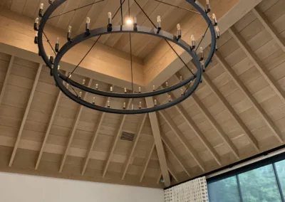 A chandelier hanging in a room with wood beams.