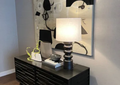 A black dresser in a room with a painting on it.