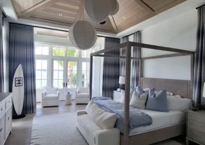 A bedroom with a four poster bed and a large window.