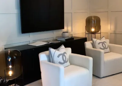 A living room with two white chairs and a tv.